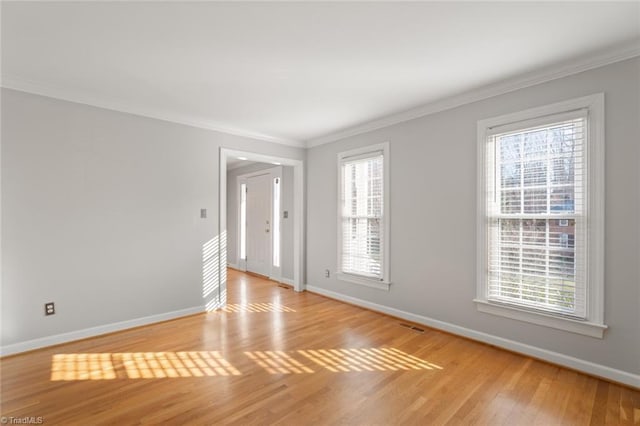 empty room featuring light hardwood / wood-style flooring, crown molding, and plenty of natural light