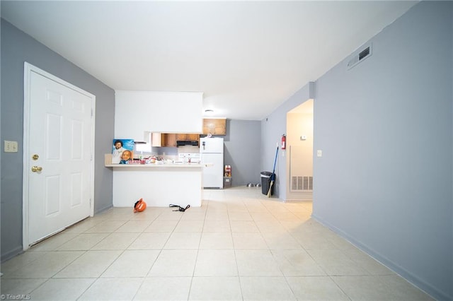 kitchen with white fridge, fume extractor, kitchen peninsula, and light tile flooring