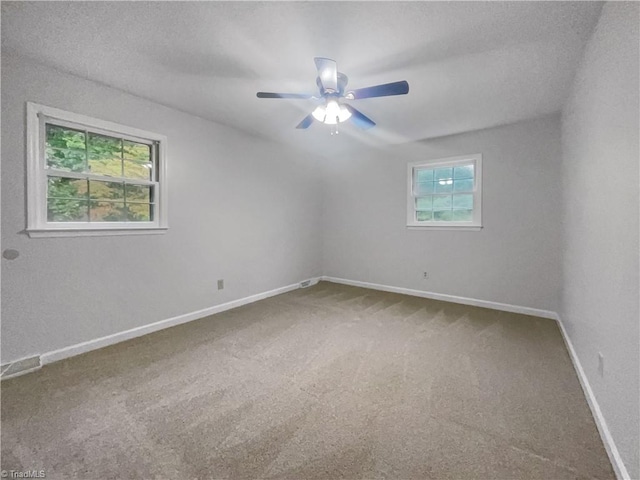 spare room featuring ceiling fan, carpet floors, and a wealth of natural light