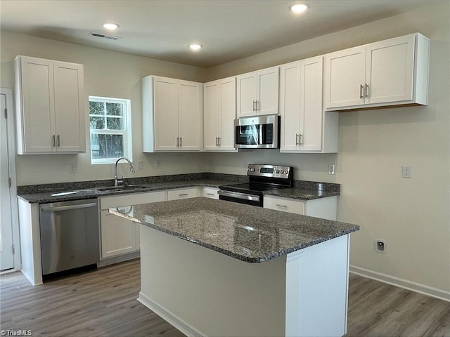 kitchen with wood-type flooring, white cabinetry, sink, a center island, and stainless steel appliances