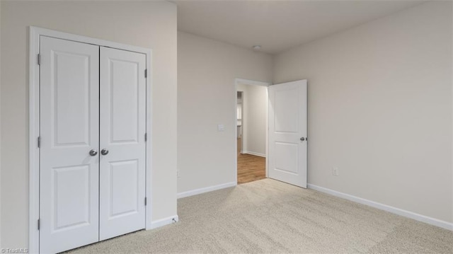 unfurnished bedroom featuring light carpet and a closet