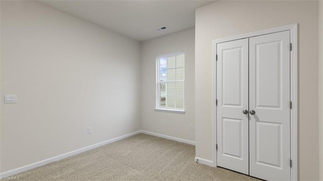 unfurnished bedroom featuring light carpet and a closet