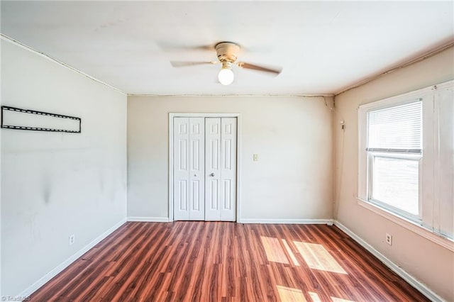 unfurnished bedroom with a ceiling fan, wood finished floors, baseboards, and a closet