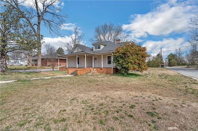 view of front of house featuring covered porch, a chimney, and a front lawn