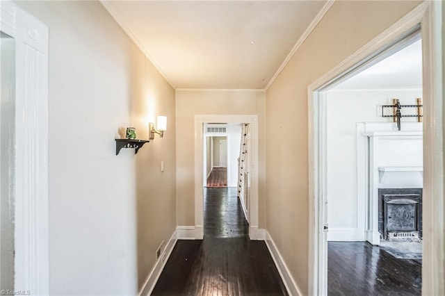 hallway featuring baseboards, crown molding, and dark wood-type flooring