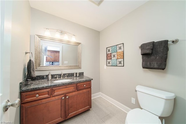 bathroom with toilet, baseboards, vanity, and tile patterned flooring