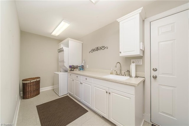 laundry area with stacked washer / dryer, cabinet space, and baseboards