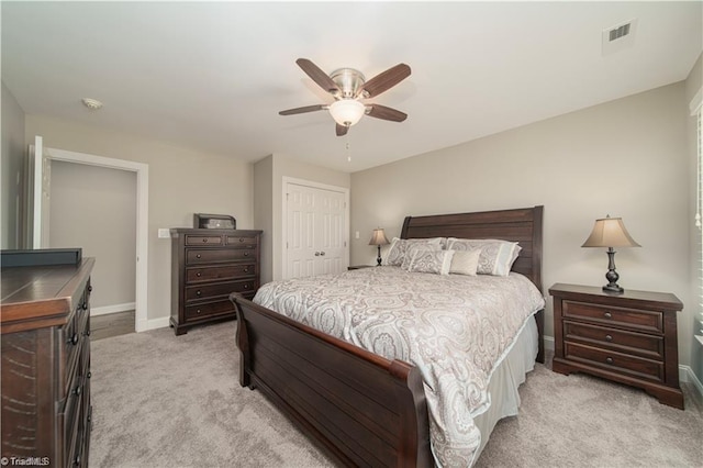 bedroom featuring light colored carpet, a closet, baseboards, and a ceiling fan