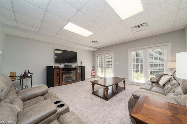 living room featuring a drop ceiling, carpet flooring, and baseboards