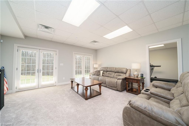 living room featuring french doors, a drop ceiling, plenty of natural light, carpet flooring, and baseboards