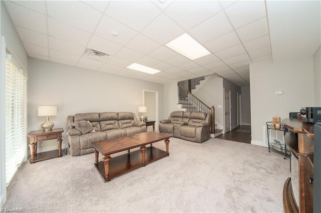 living room featuring carpet floors, stairs, a paneled ceiling, plenty of natural light, and baseboards