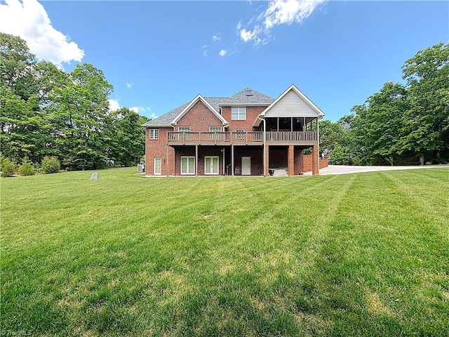 back of property featuring a yard, brick siding, a wooden deck, and a sunroom