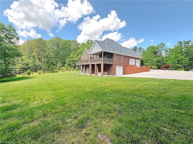 back of house featuring brick siding, concrete driveway, a lawn, a garage, and a wooden deck