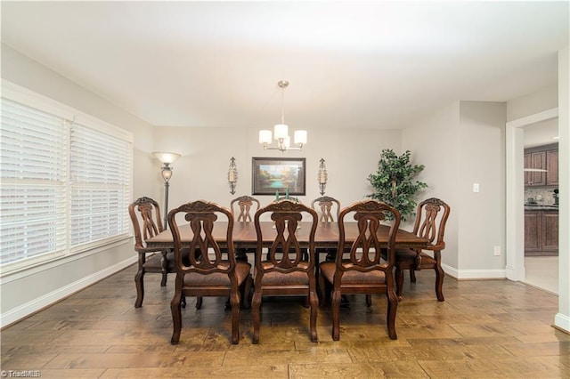 dining room with a chandelier, baseboards, and wood finished floors