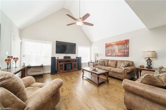 living room featuring high vaulted ceiling, a ceiling fan, light wood-style flooring, and plenty of natural light