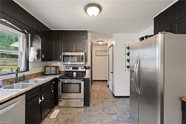 267 Pine Ridge Trl, Pinnacle, NC 27043 - kitchen featuring appliances with stainless steel finishes, stone finish flooring, decorative backsplash, a textured ceiling, and dark cabinetry