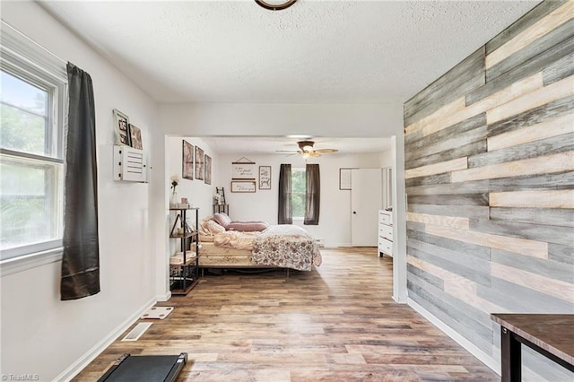 267 Pine Ridge Trl, Pinnacle, NC 27043 - bedroom featuring wood finished floors, a textured ceiling, wood walls, and a ceiling fan