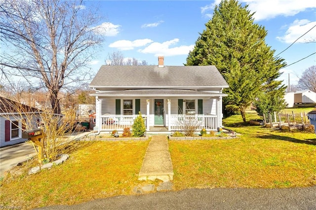 view of front of house featuring covered porch, a chimney, a front lawn, and roof with shingles