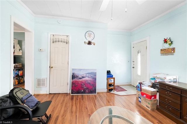 interior space featuring light wood-style flooring, visible vents, and ornamental molding