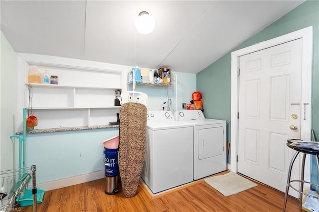 clothes washing area with baseboards, light wood-style flooring, laundry area, and washer and clothes dryer