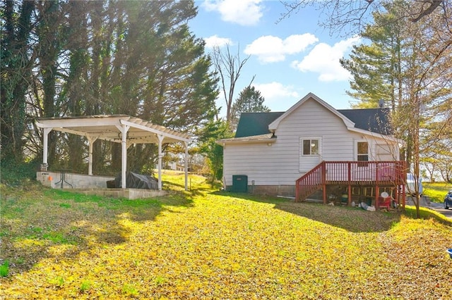 back of property with a wooden deck, a lawn, and a carport