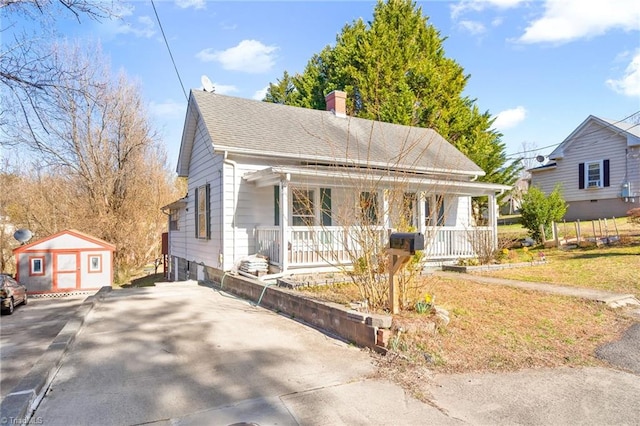 bungalow-style house featuring a front yard, roof with shingles, covered porch, a chimney, and an outdoor structure