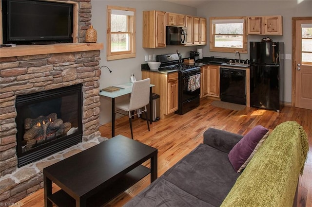 kitchen with light hardwood / wood-style flooring, sink, a fireplace, and black appliances