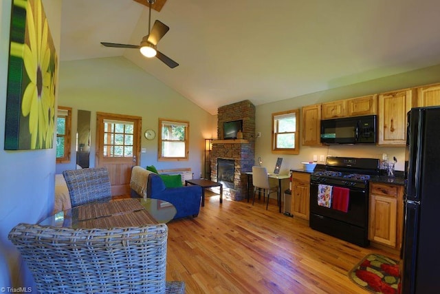 kitchen featuring ceiling fan, black appliances, brick wall, light hardwood / wood-style floors, and a stone fireplace