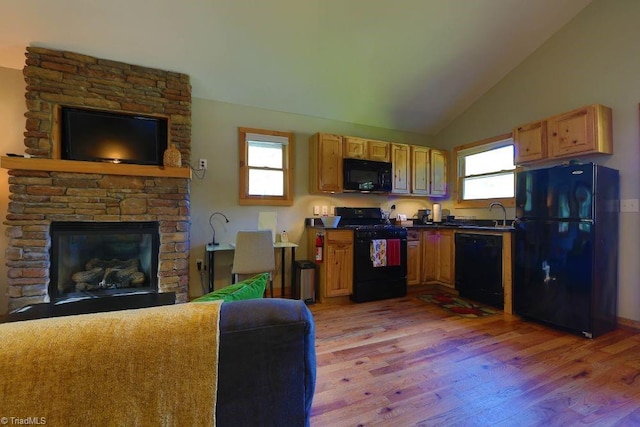 kitchen featuring plenty of natural light, light hardwood / wood-style floors, a fireplace, and black appliances