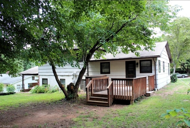 back of property with a deck and a lawn