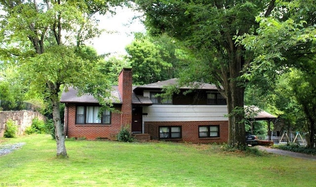 tri-level home featuring a front yard, brick siding, and a chimney