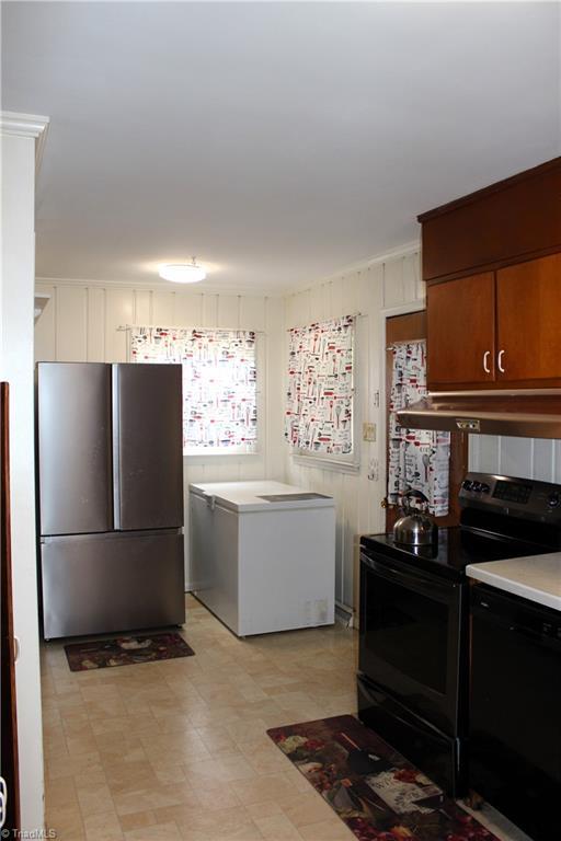 kitchen featuring light floors, light countertops, under cabinet range hood, and black appliances