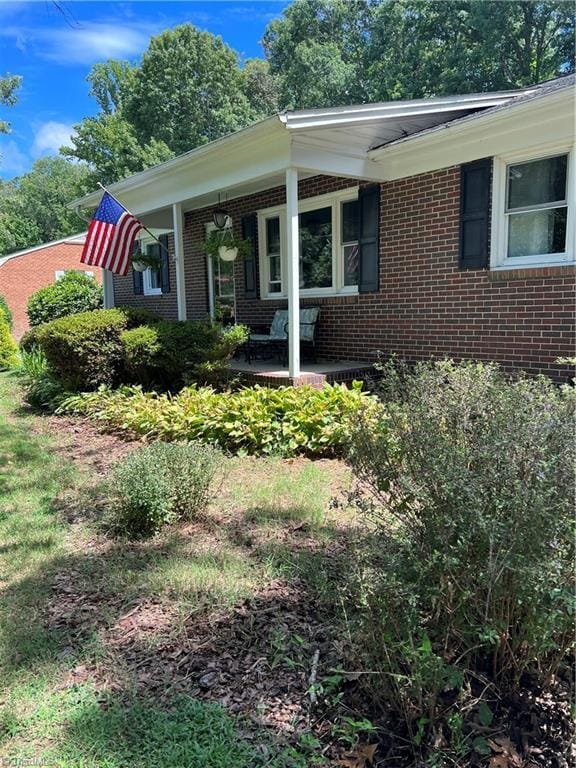 view of front of home featuring brick siding and a porch