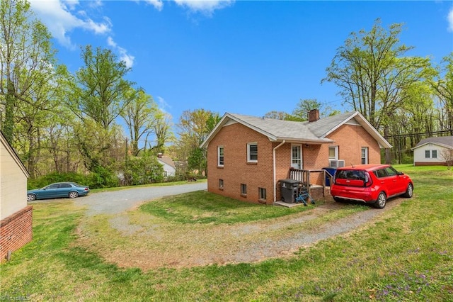 4478 Ogburn Ave, Winston-Salem, NC 27105 - view of side of home featuring brick siding, driveway, a lawn, and a chimney