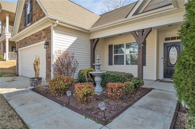 view of exterior entry featuring an attached garage, stone siding, concrete driveway, and roof with shingles