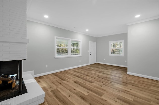 unfurnished living room featuring a brick fireplace, crown molding, and light wood-type flooring