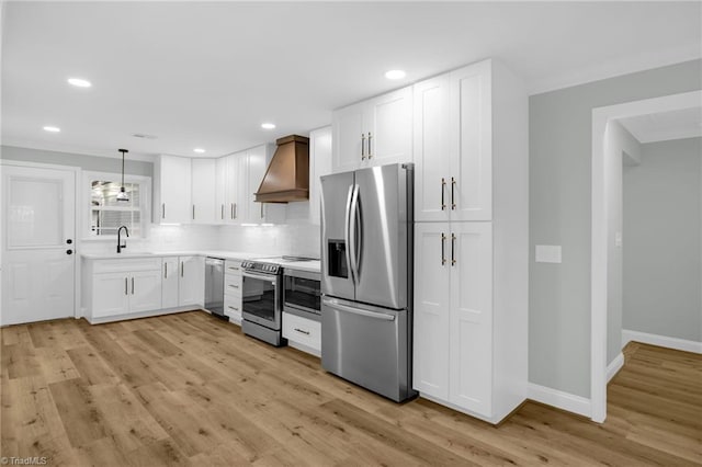 kitchen with premium range hood, sink, white cabinetry, decorative light fixtures, and stainless steel appliances