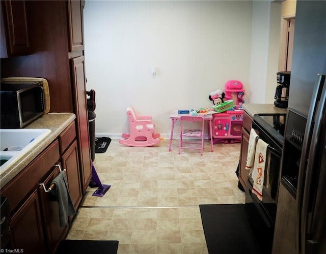 kitchen with a sink, stainless steel appliances, baseboards, and light countertops