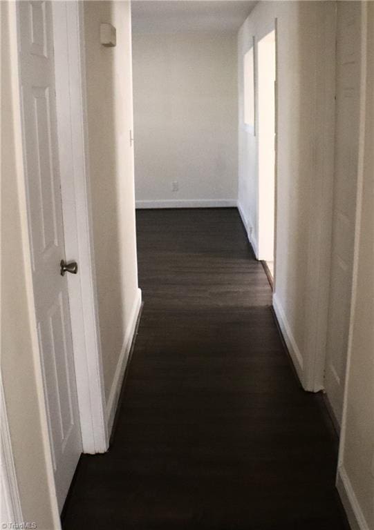 hallway featuring baseboards and dark wood finished floors