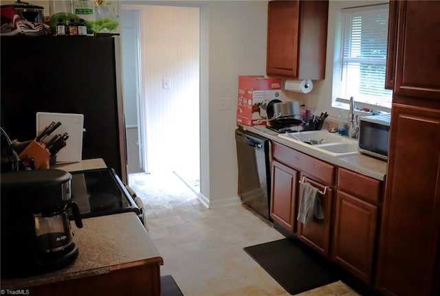 kitchen featuring baseboards, light floors, light countertops, stainless steel appliances, and a sink