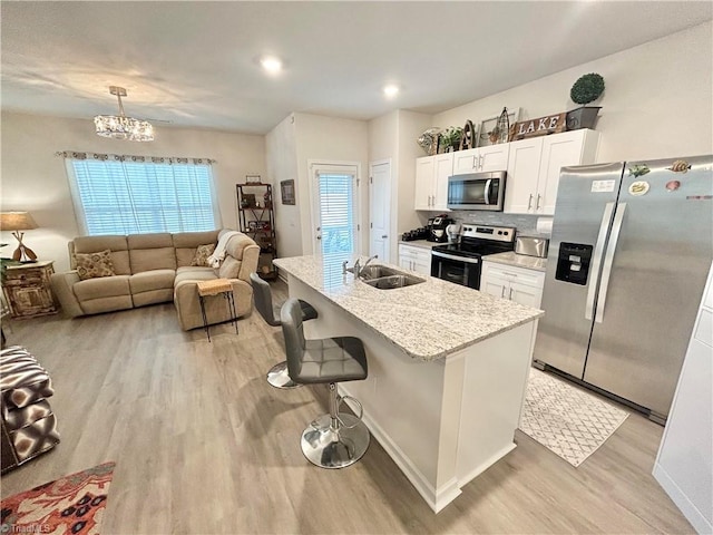 kitchen with sink, a breakfast bar, white cabinetry, a kitchen island with sink, and stainless steel appliances