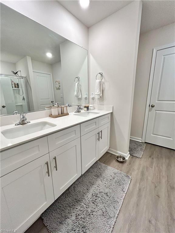 bathroom with wood-type flooring, vanity, and walk in shower