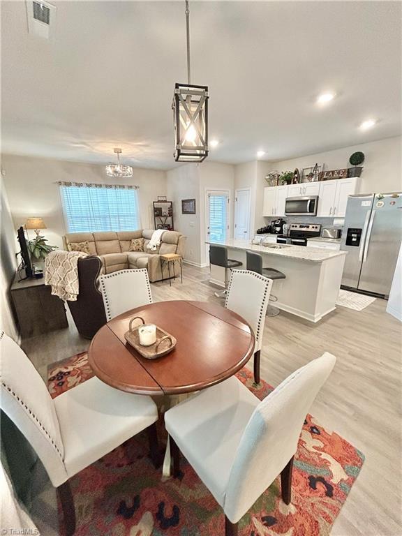 dining area featuring an inviting chandelier and light hardwood / wood-style floors