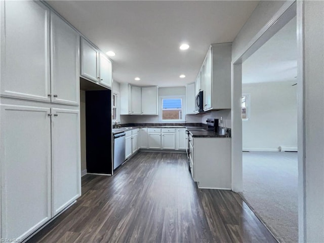 kitchen featuring dark wood finished floors, stainless steel appliances, dark countertops, recessed lighting, and white cabinets