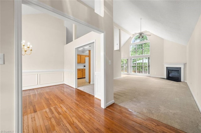 145 Millers Crossing Ct, Winston-Salem, NC 27103 - unfurnished living room featuring high vaulted ceiling, light wood-style flooring, a fireplace with flush hearth, a chandelier, and a ceiling fan
