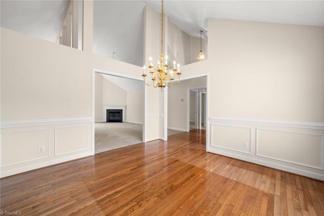 145 Millers Crossing Ct, Winston-Salem, NC 27103 - spare room featuring a chandelier, a fireplace, wood finished floors, a wainscoted wall, and a towering ceiling