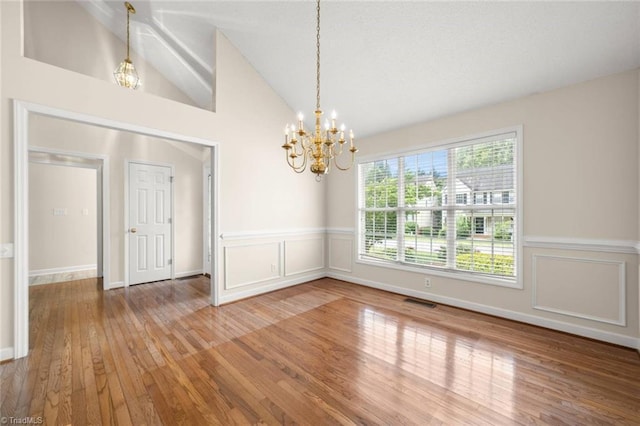 145 Millers Crossing Ct, Winston-Salem, NC 27103 - unfurnished room with wood finished floors, a chandelier, lofted ceiling, wainscoting, and a decorative wall