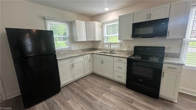 1004 Tabor St, High Point, NC 27262 - kitchen with black appliances, a sink, light wood-style floors, and light stone countertops