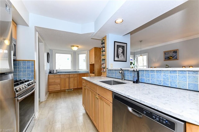 kitchen featuring sink, appliances with stainless steel finishes, light stone counters, tasteful backsplash, and decorative light fixtures