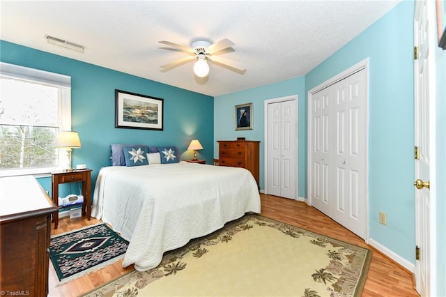 bedroom featuring ceiling fan, two closets, and light wood-type flooring